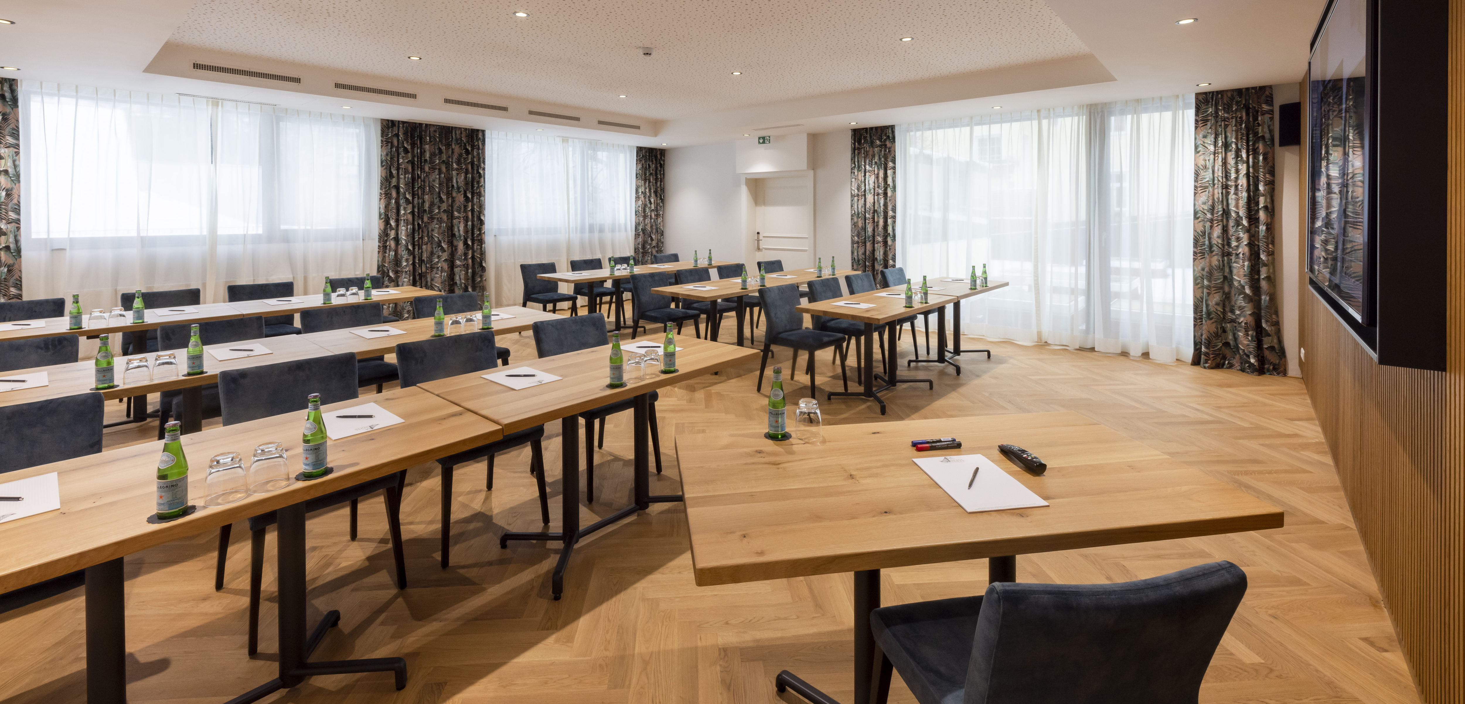 Bright, modern conference room with wooden tables, chairs and daylight windows.